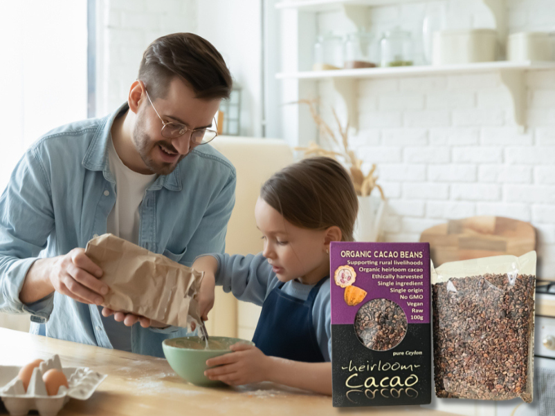 Father and child baking at home with Ceylon Kokonati cacao nibs box and pouch on the counter.